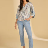 Woman wearing a floral blouse and jeans on a beige background
