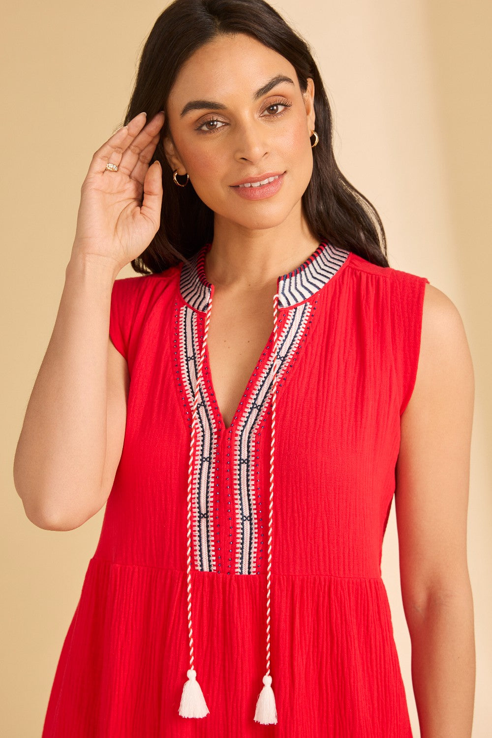 Woman wearing a red dress with intricate details on a beige background