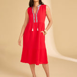 Woman wearing a red dress with white embroidery on a beige background