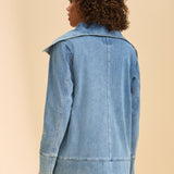 Person wearing a light blue denim jacket on a beige background