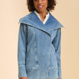 Woman wearing a blue denim jacket and pants on a beige background