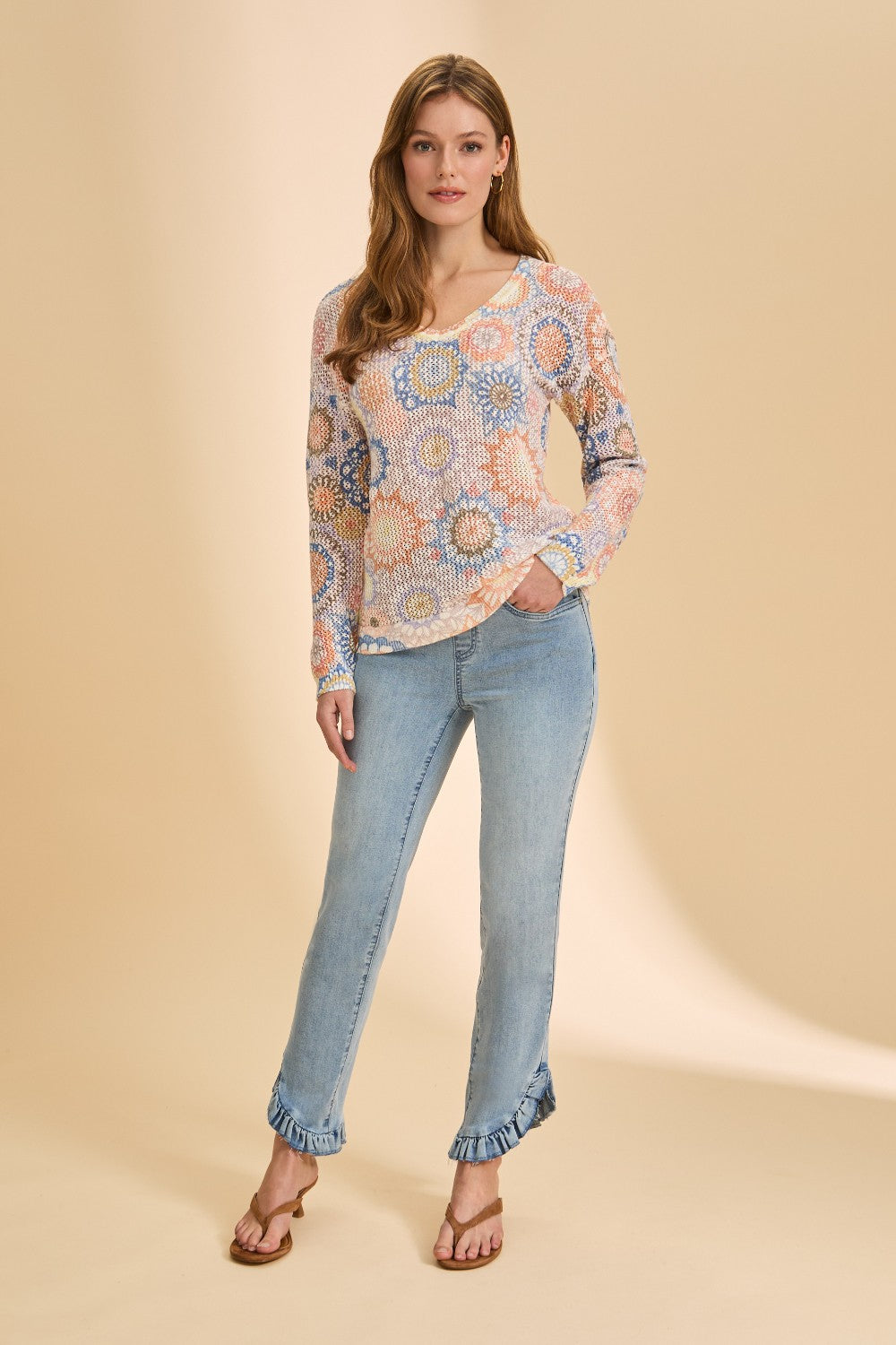 Woman wearing a patterned blouse and jeans on a beige background