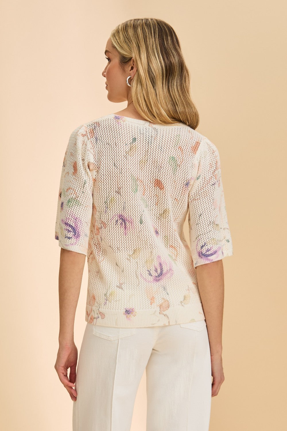 Woman wearing a floral-patterned knit top against a beige background