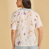 Woman wearing a floral top with a beige background