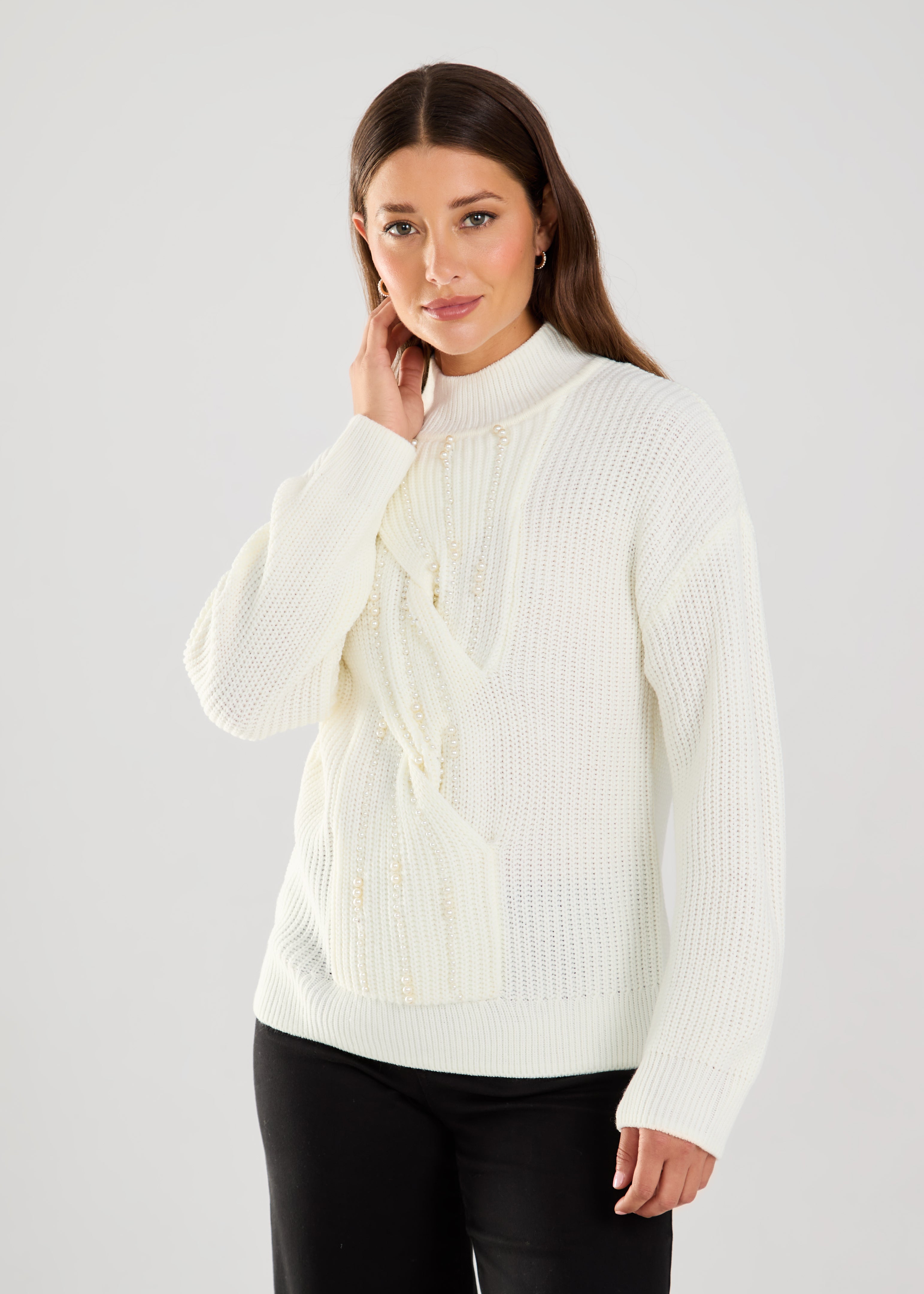 This cable knit sweater features delicate pearl embellishments, adding a touch of sophistication to a classic design.