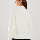 This cable knit sweater features delicate pearl embellishments, adding a touch of sophistication to a classic design.