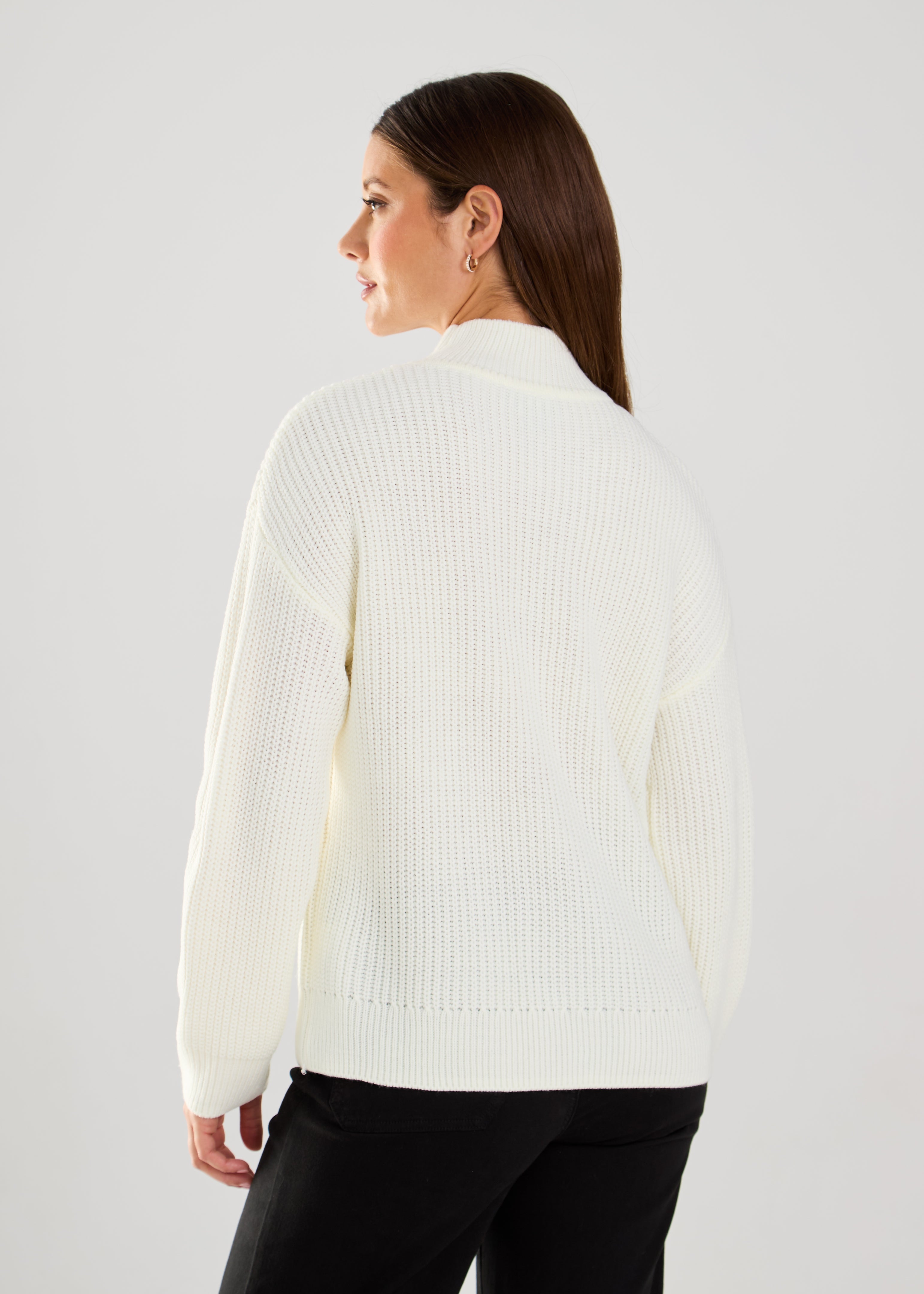 This cable knit sweater features delicate pearl embellishments, adding a touch of sophistication to a classic design.