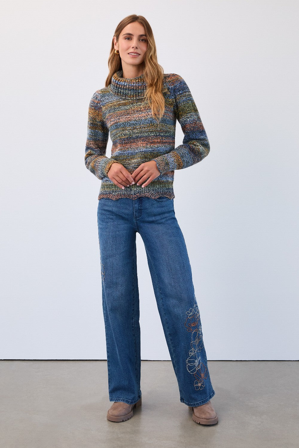 Woman wearing a patterned sweater and blue jeans against a white background