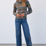 Woman wearing a patterned sweater and blue jeans against a white background