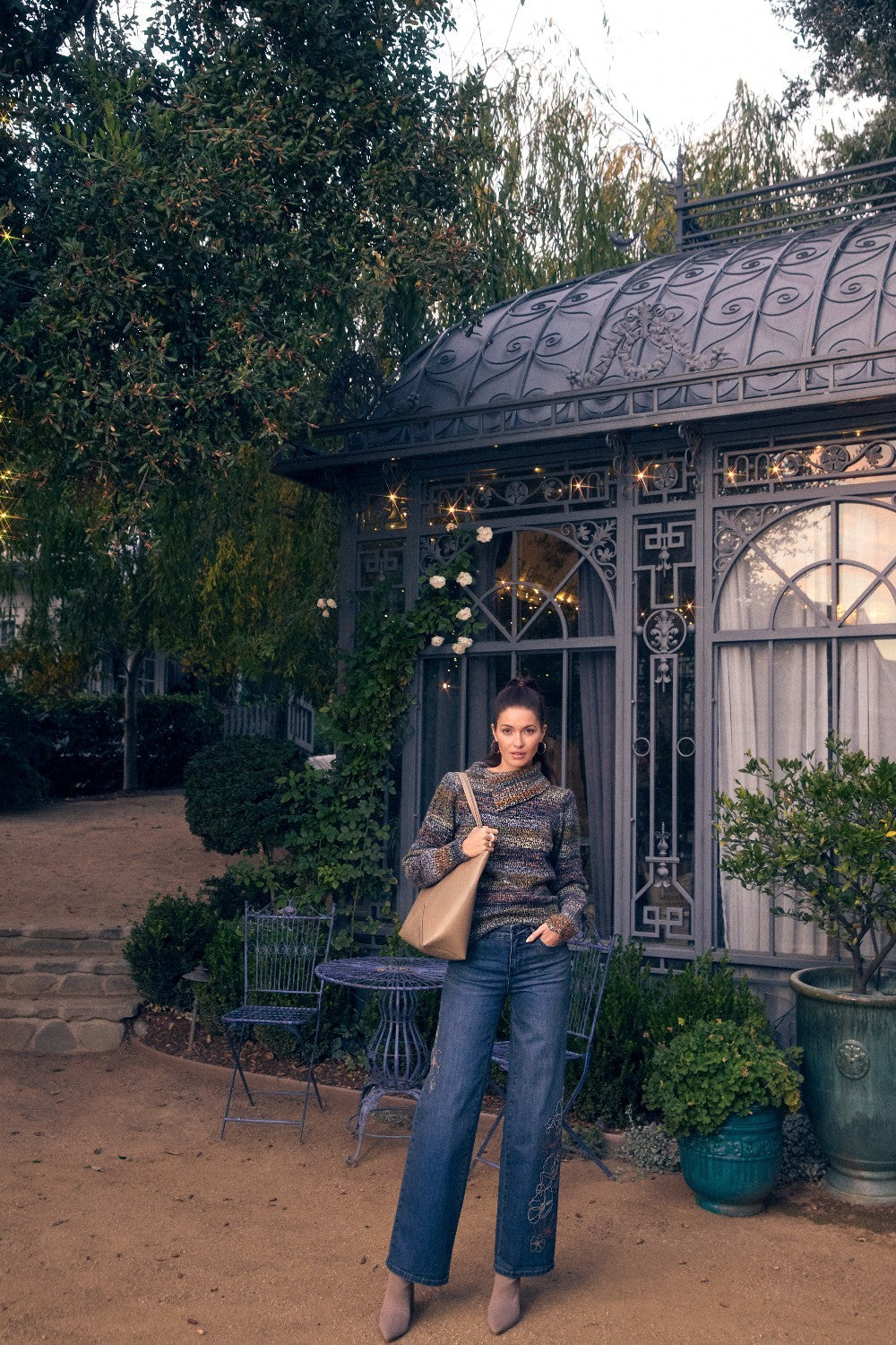 Woman standing in a garden with decorative building and plants