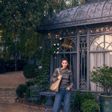 Woman standing in a garden with decorative building and plants