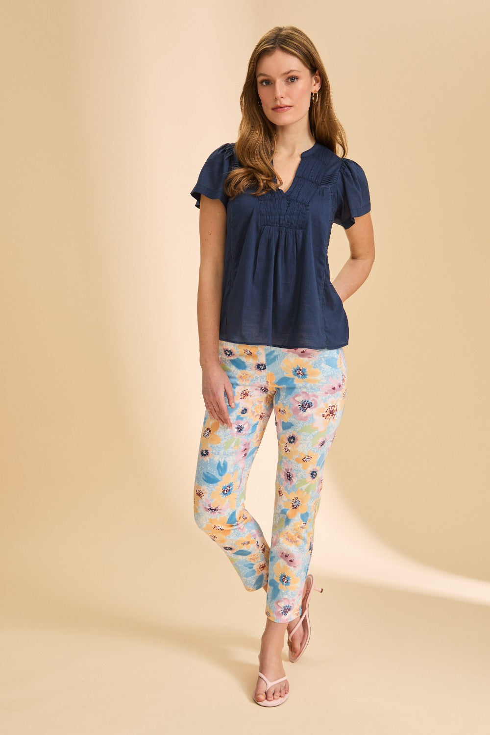 Person wearing a short sleeve navy blouse with patterned pant on beige background