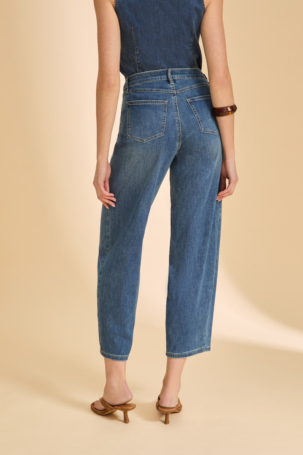 Person wearing blue jeans on a beige background