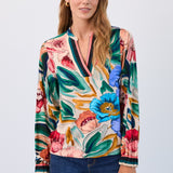 Woman wearing a colourful floral blouse with a plain background
