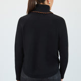 Person wearing a black turtleneck sweater and dark jeans on a white background