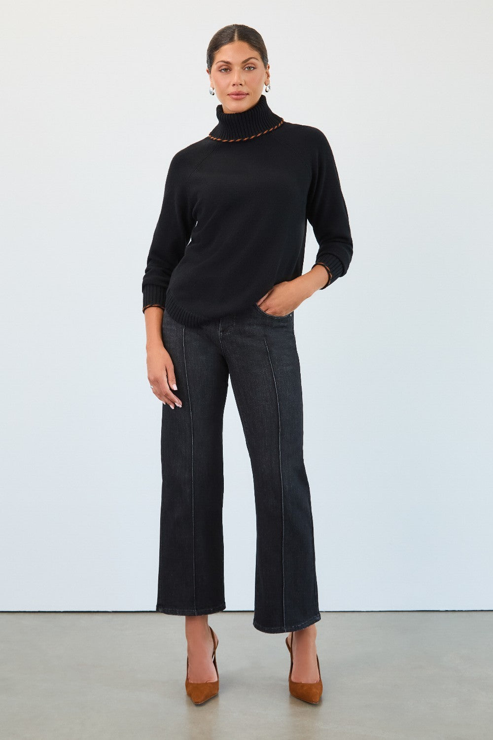 Person wearing a black turtleneck and dark jeans against a white background