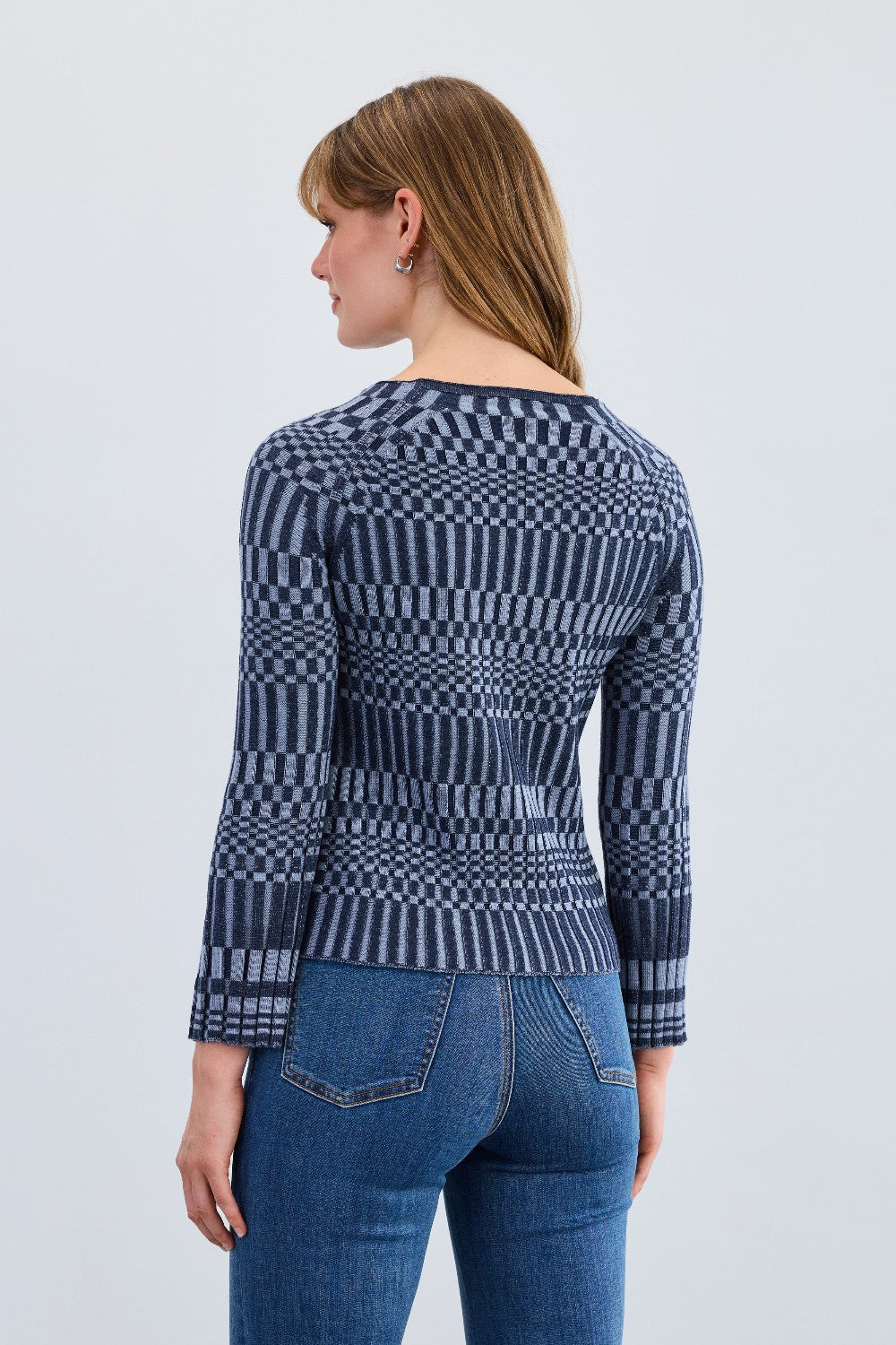 Woman wearing a blue patterned sweater and jeans on a white background