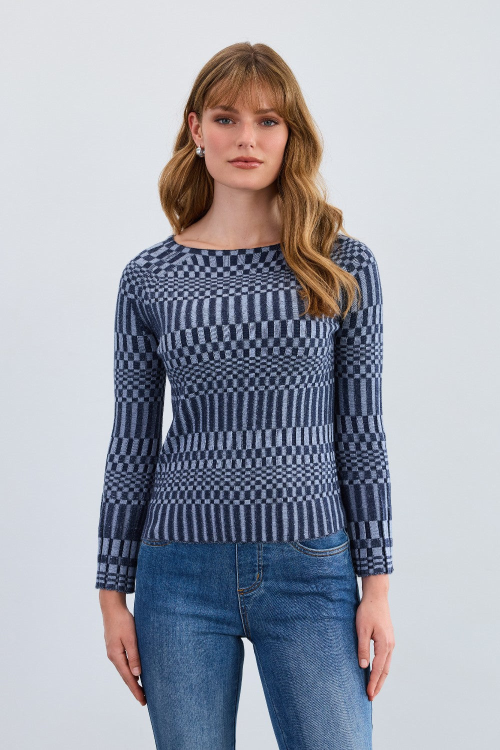 Woman wearing a blue patterned sweater and jeans on a light gray background