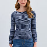 Woman wearing a blue patterned sweater and jeans on a light gray background