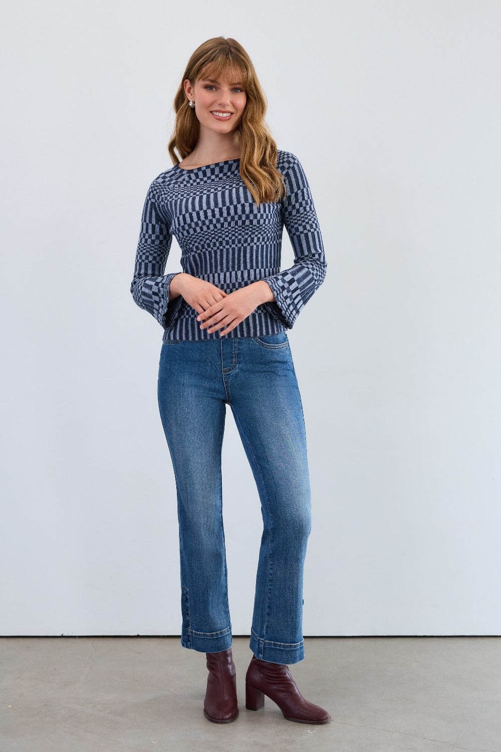 Woman wearing a patterned sweater and blue jeans against a white background