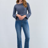 Woman wearing a patterned sweater and blue jeans against a white background