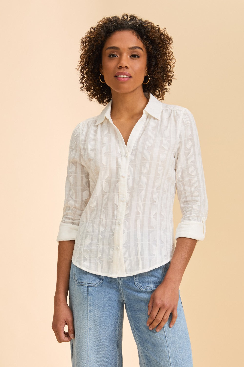 Person wearing a white shirt with jeans against a beige background