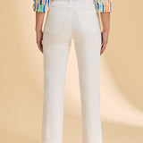 Person wearing a colorful shirt and white pants on a beige background