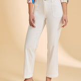 Person wearing a colorful striped shirt and white pants on a beige background