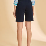 Person wearing navy shorts and a striped shirt on a beige background