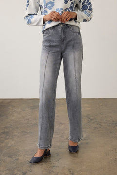 Woman wearing a gray wide leg jean with a printed top and pumps on a neutral background.