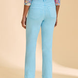 Blue ankle pant paired with patterned top against beige background