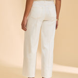 Person wearing ivory pants and a striped shirt on a beige background