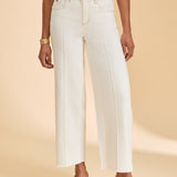 Person wearing ivory pants and a striped shirt on a beige background