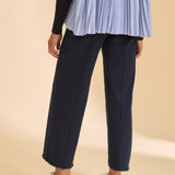 Person wearing navy pants and a blue checkered top on a beige background