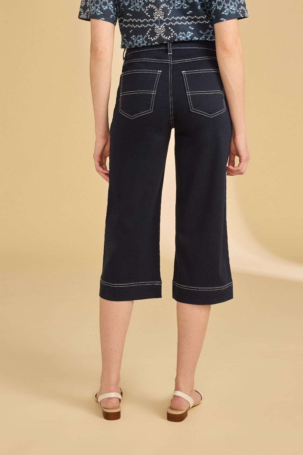 Person wearing dark blue wide-leg jeans on a beige background