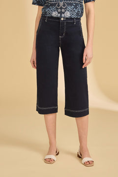 Person wearing dark blue wide-leg jeans on a beige background