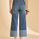 Person wearing blue jeans and a striped shirt on a beige background