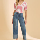 Woman wearing a striped shirt and blue jeans against a beige background