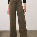 Person wearing a green wide leg pant with a black top and black shoes on a neutral background.