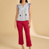 Woman wearing a patterned top and red pants on a beige background