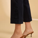 Navy blue pants with button details worn by a person on a beige background