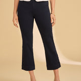 Person wearing navy capri pants and a white top on a beige background