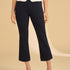 Person wearing navy capri pants and a white top on a beige background