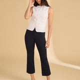 Woman wearing a white sleeveless blouse and black pants on a beige background