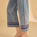 Denim pants with decorative hem on a beige background