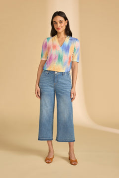 Woman wearing a colorful shirt and blue jeans on a beige background