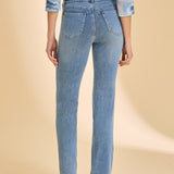 Person wearing a patterned top with light blue denim straight leg jeans