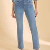 Person wearing a patterned top with light blue denim straight leg jeans