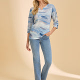 Person wearing a patterned top with light blue denim straight leg jeans