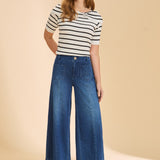 Woman wearing a striped shirt and blue jeans on a beige background